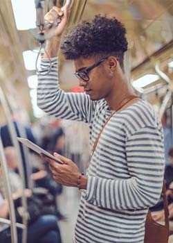 A young man on the subway looking at his tablet.